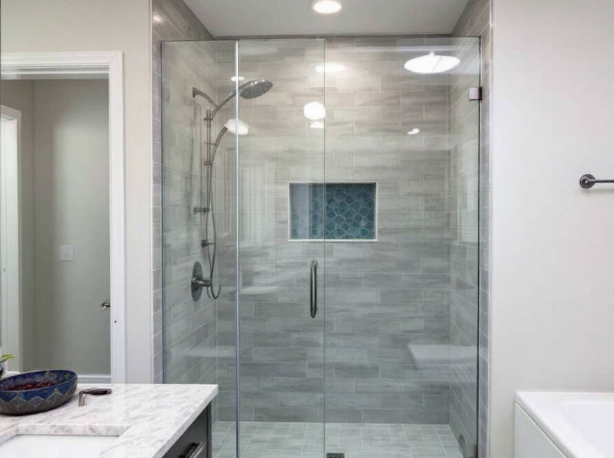 An expert craftsman from Boston installing custom shower doors with a modern, contemporary design in a newly designed bathroom.