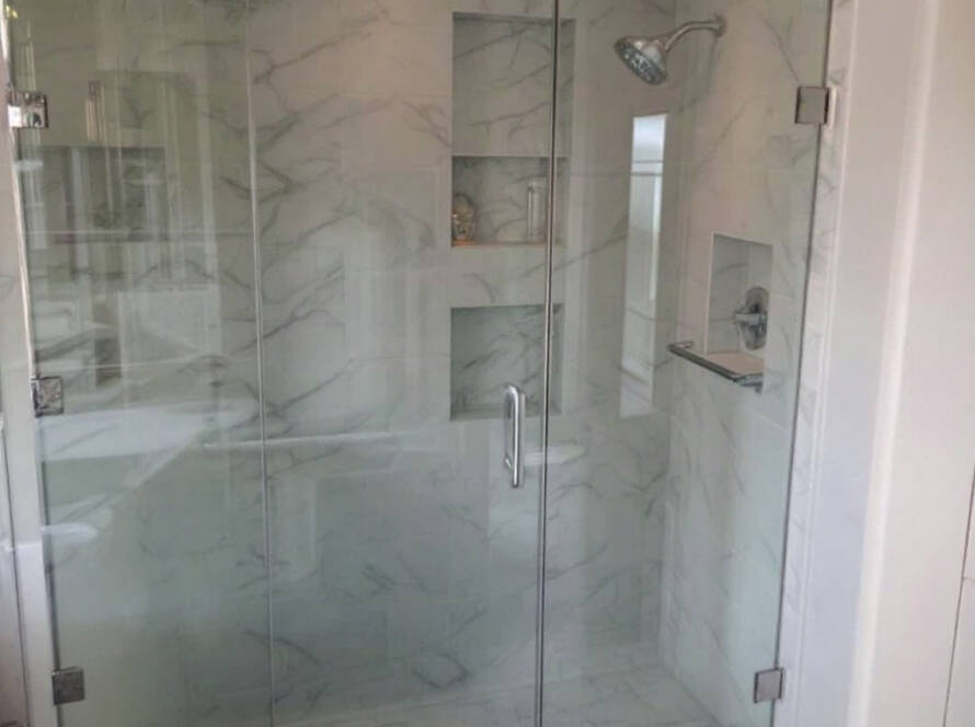 Skilled workmen installing a modern and elegant shower door in a residence near Hingham, MA.