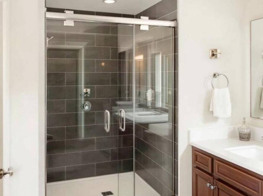 Professional shower installers fitting a contemporary style glass shower in a modern bathroom near Milton, MA.