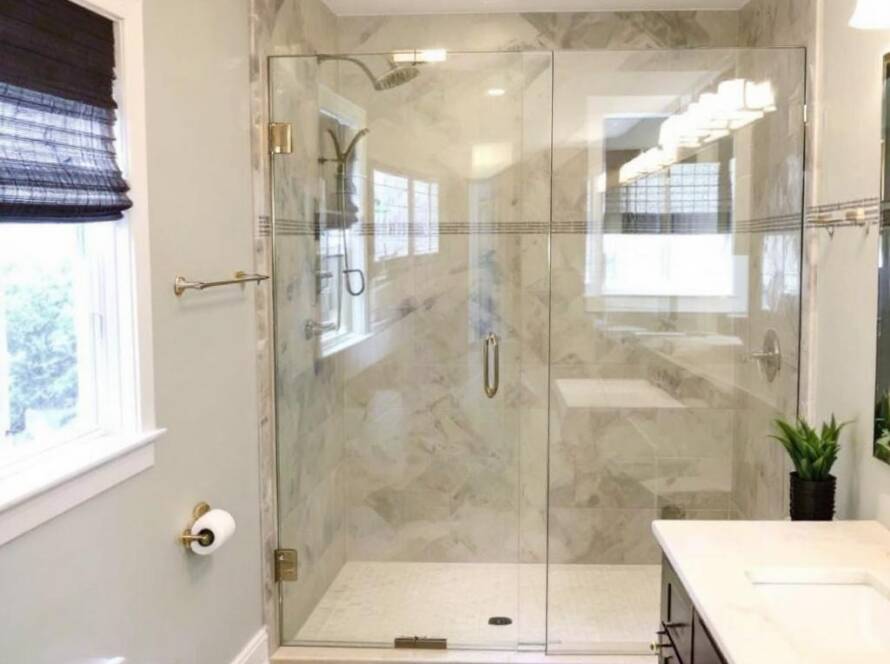A skilled professional installing a modern, frameless shower door in Weymouth, MA.