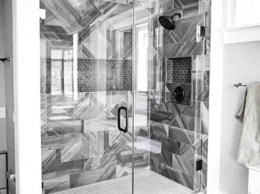 Professional setting up a sleek modern shower door in a contemporary styled bathroom near Hingham MA.